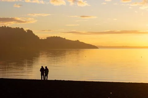 Two man having a chat on the lake beach at sunset in Pucon, Chile Stock Photos