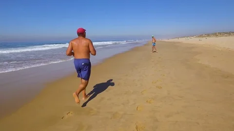 Two Man Jogging Along Wave of Sea Water Stock Footage 84110723