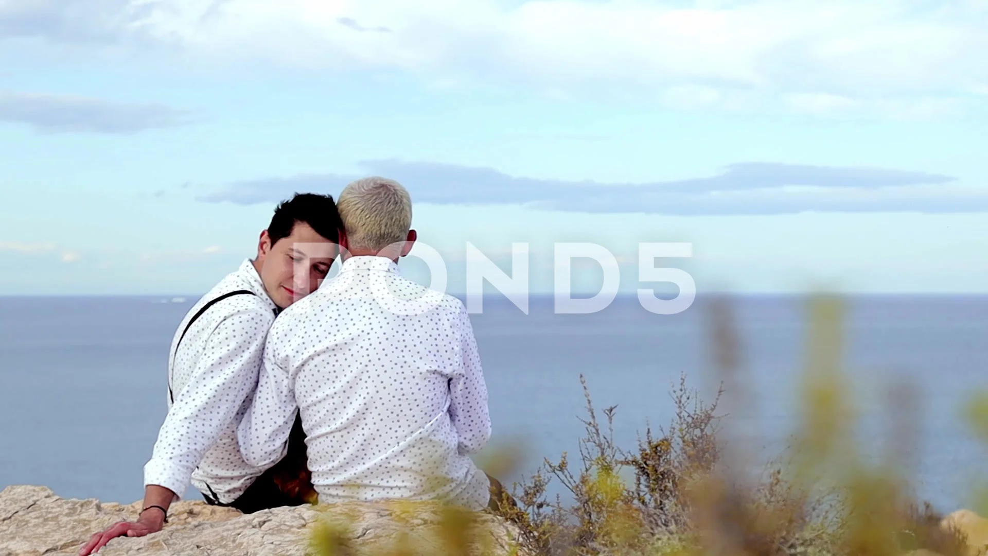 Two man in love. Gay couple spend time in nature. Men sitting on rock by