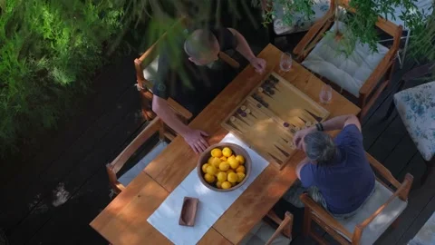Two man playing backgammon on patio under trees. 4K Stock Footage 195654929