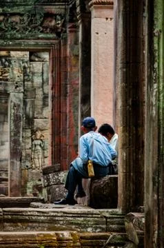 Two man sitting between stone doors Stock Photos
