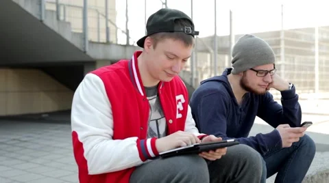 Two man sitting on wall with tablet mobile phone. Stock Footage 49535627