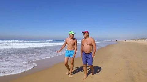 Two Man Walking Along Wave of Sea Water Stock Footage 84110264