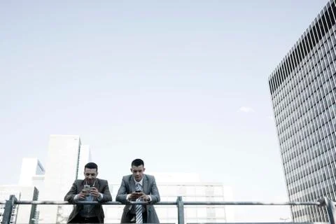 Two managers checking their smartphones during a break Stock Photos