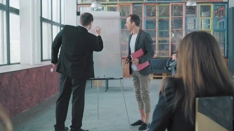 Two managers hold a presentation in the audience near the flipchart, draw charts Stock Footage 108034831