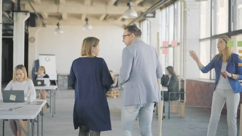 Two managers a man and a woman walk around the office, approach a colleague who Stock Footage 108874686