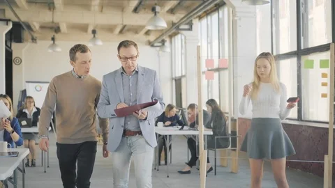 Two managers walk around the office, approach colleagues, communicate and Stock Footage 108873091
