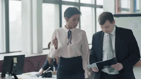 Two managers, a woman and a man walk in the office and discuss the project Stock Footage 124274307