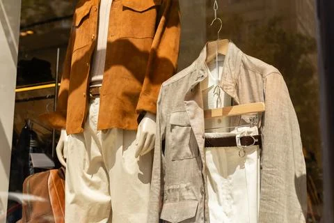 Two mannequins stand in a store window showing casual outfits. One wears a .. Stock Photos