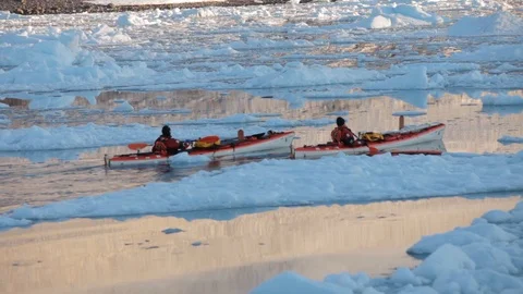 Two mans moving on kayaks moving in the middle of Arctic Ocean in the sunset Vidéo 100872392