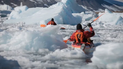 Two mans moving on kayaks moving in the middle of Arctic Ocean, Greenland Stock Footage 100872557