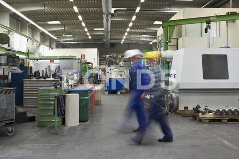 Two manual workers walking through a factory, blurred motion, long exposure Stock Photos