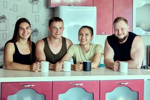 Two married couples met in kitchen of rented house, group portrait. Stock Photos