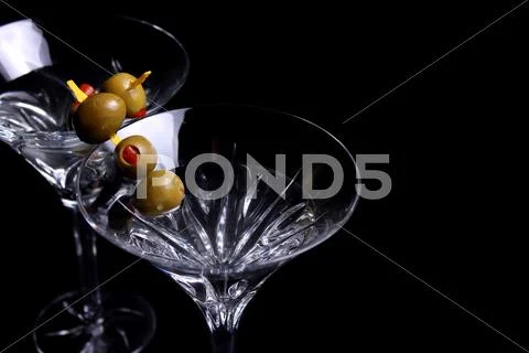 Two martini glasses with olives on black Stock Photos