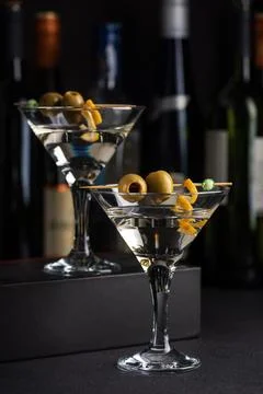Two martini glasses with skewered green olives and citrus twists against da.. Stock Photos