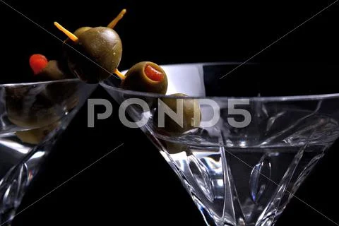 Two martinis on black with olives Stock Photos
