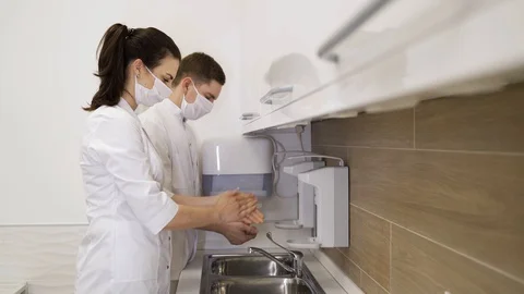 Two masked doctors wash their hands in hospital during pandemic Stock Footage 130019450