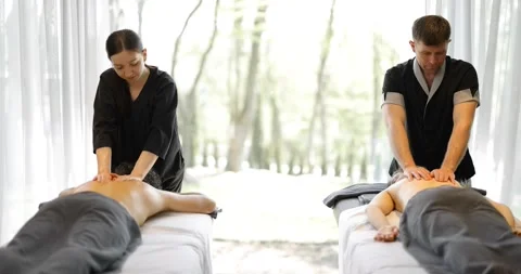 Two masseurs doing a deep back massage to a couple Stock Footage 154832054