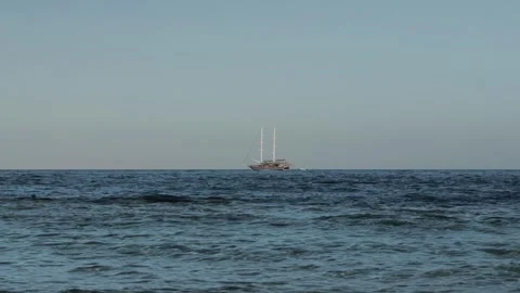 Two-masted sailing ship Brig with lowered sails floats on sea on horizon. Cruise Stock Footage 307204277