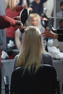 Two masters at the same time dried with hair dryers hair blonde model in beau Fotos Stock