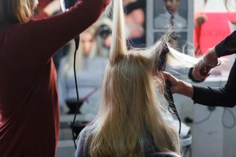 Two masters at the same time dried with hair dryers hair blonde model in beau Stock Photos