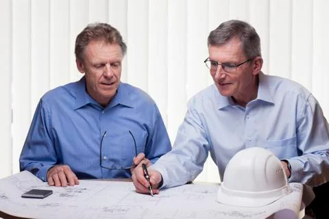 Two mature architects or engineers discussing a construction plan in a bright Stock Photos