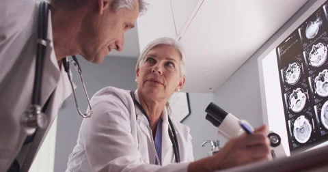 Two mature white doctors analyzing x-rays Video stock 58219472