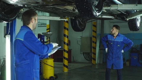 Two Mechanic checking on a car engine and taking notes Stock Footage 70645059