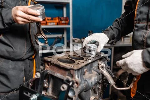 Two mechanic holding a new piston for the engine, overhaul.. Engine on a repair Stock Photos