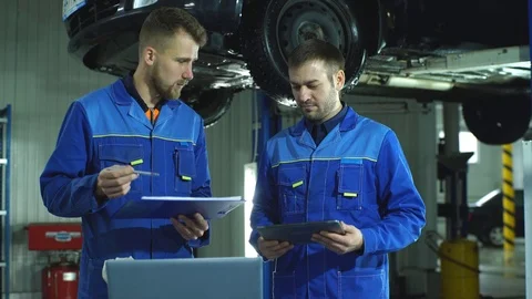 Two mechanic with a tablet recording the diagnostic information of the car Stock Footage 70642878