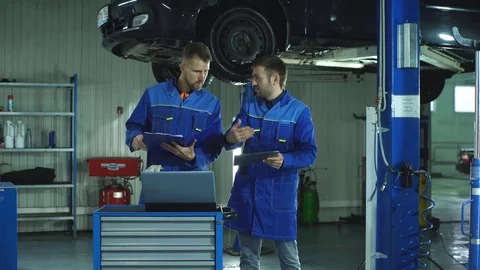 Two mechanic with a tablet recording the diagnostic information of the car Stock Footage 70643910