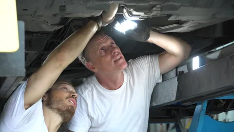 Two mechanic using flashlight   inspection to undercarriage of car in worksho Stock Footage 147369791