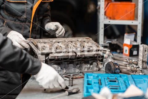 Two mechanics disassembling the engine, overhaul.. Engine on a repair stand with Stock Photos