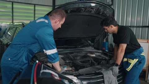 Two mechanics examine a car engine together Vidéo 345031564