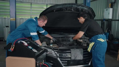 Two mechanics examine a car engine together 스톡 동영상 345031597