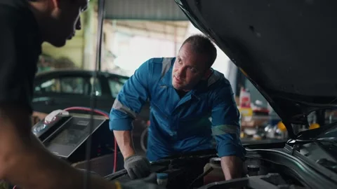 Two mechanics examine a car engine together Stockbeeldmateriaal 345031645