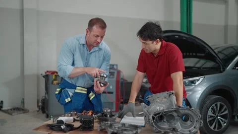 Two mechanics examine engine parts at a repair shop 库存影片 339546185