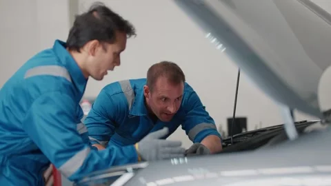 Two mechanics examine a EV car engine together 库存影片 339050247