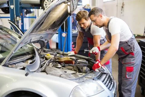 Two mechanics fixing car in a workshop Stock Photos