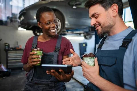 Two mechanics having a coffee break and discussing work in a garage Stock Photos