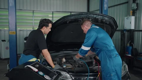 Two mechanics inspect car engine under hood 스톡 동영상 345031581