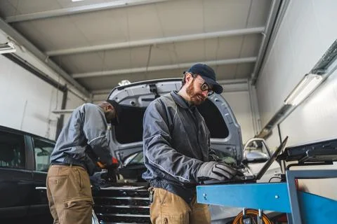 Two mechanics making computer diagnostics and checking a car at the repair shop Stock Photos