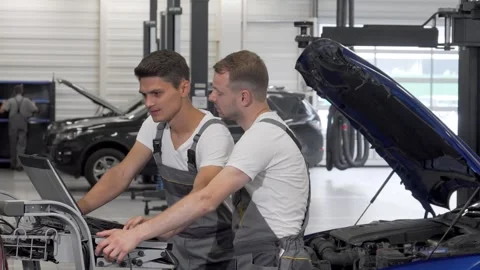 Two mechanics performing computer diagnostics on a malfunctioning car Video stock 311935710