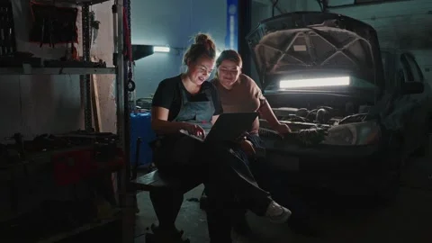 Two mechanics share knowledge while working late on a car in the garage Stock Footage 305847935