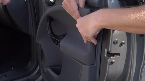 Two mechanics use a screwdriver to remove a car door trim Video stock 279024437