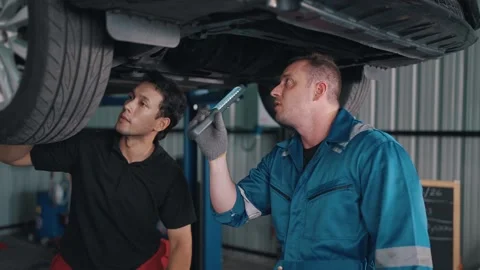 Two mechanics work beneath a raised EV car Stock-Footage 341461369