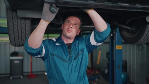 Two mechanics work beneath a raised EV car Stock-Footage 341461455