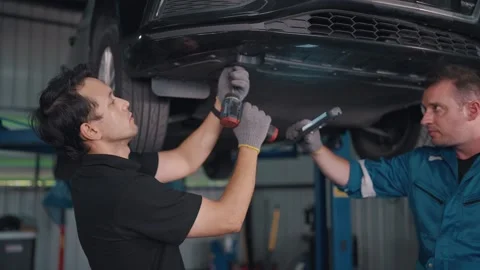 Two mechanics work under a lifted car Stock-Footage 341461339