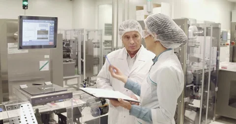 Two medecine factory engineers discussing working process, Stock Footage 101097625