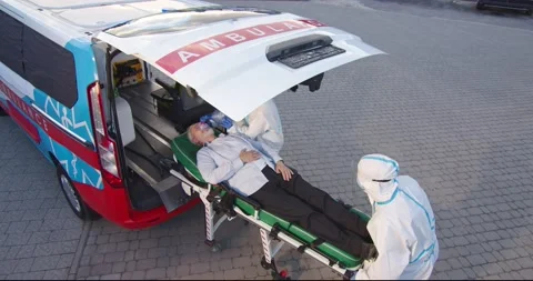 Two medics in personal protective equipment bringing old man in oxygen mask to Stock Footage 158314684